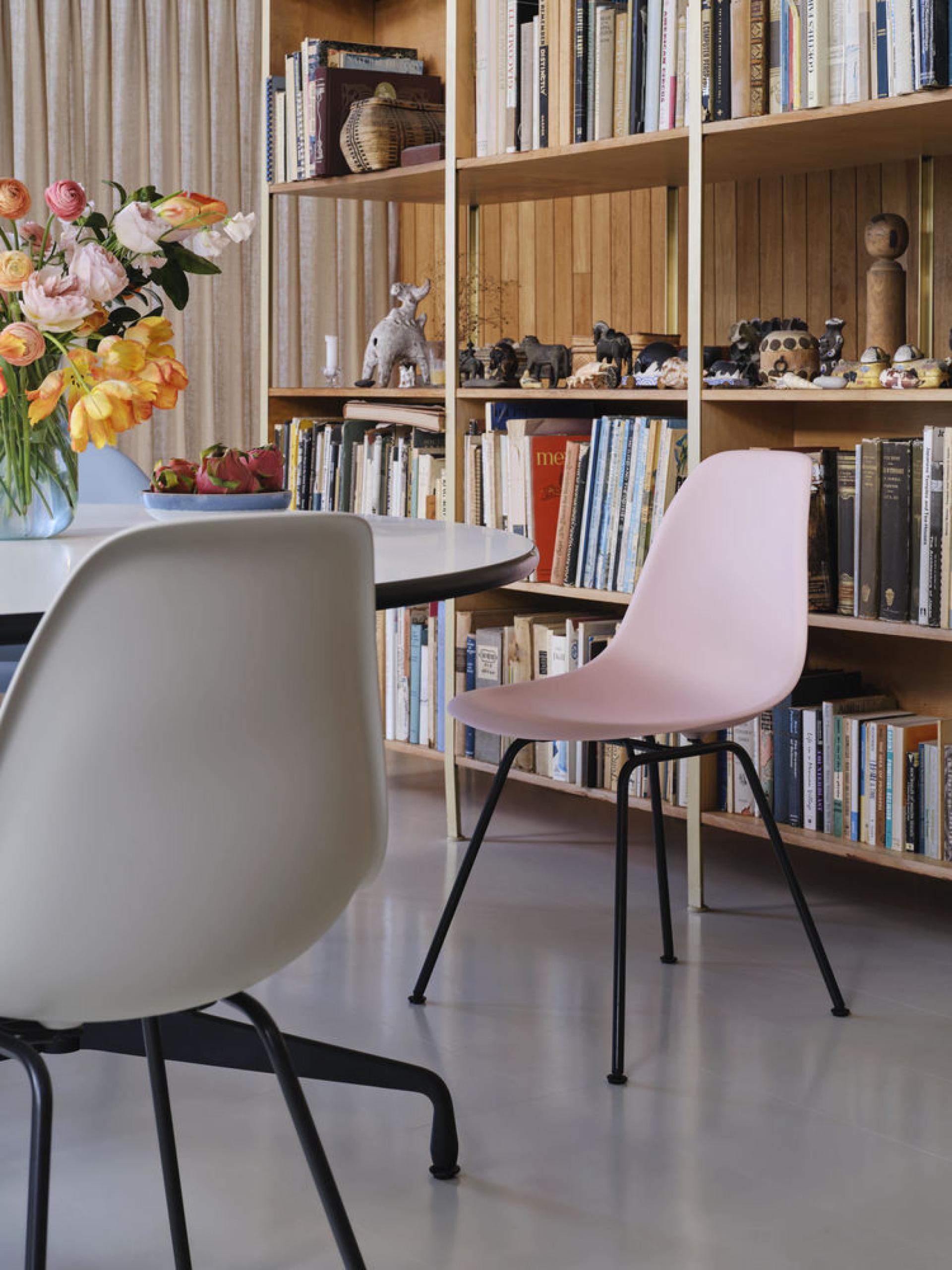 Zu sehen ist ein Eames Chair RE von Vitra vor einem Bücherregal.